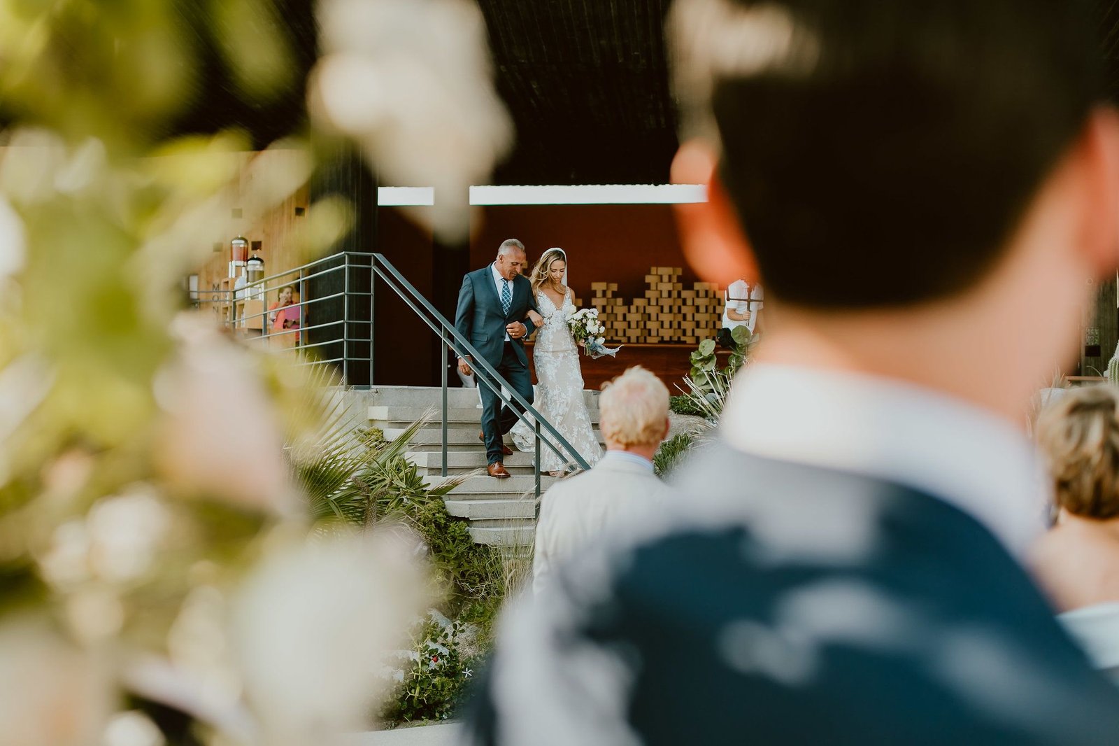 Bride walking down the stairs to her groom with her dad at The Cape by Thompson Hotels in Los Cabos. 