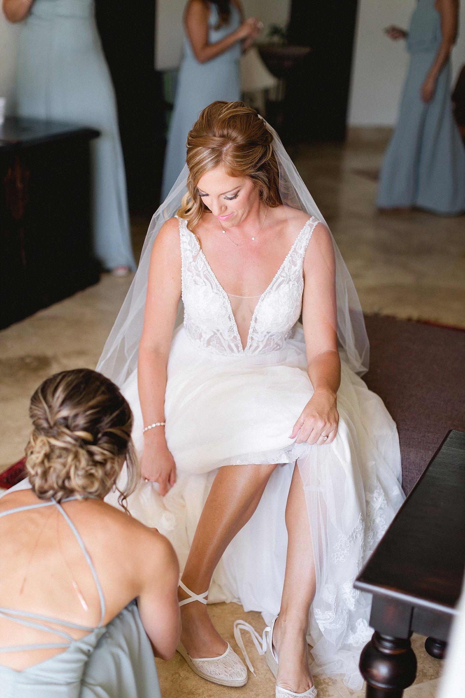 Maid of Honor helping Bride put her shoes on at her Wedding Day. They were getting ready at Hacienda Encantada in Cabo San Lucas, Mexico, and theiir wedding was at Flora Farms. Wedding PLanning by Cabo Wedding Services and Photography by Sara Richardson