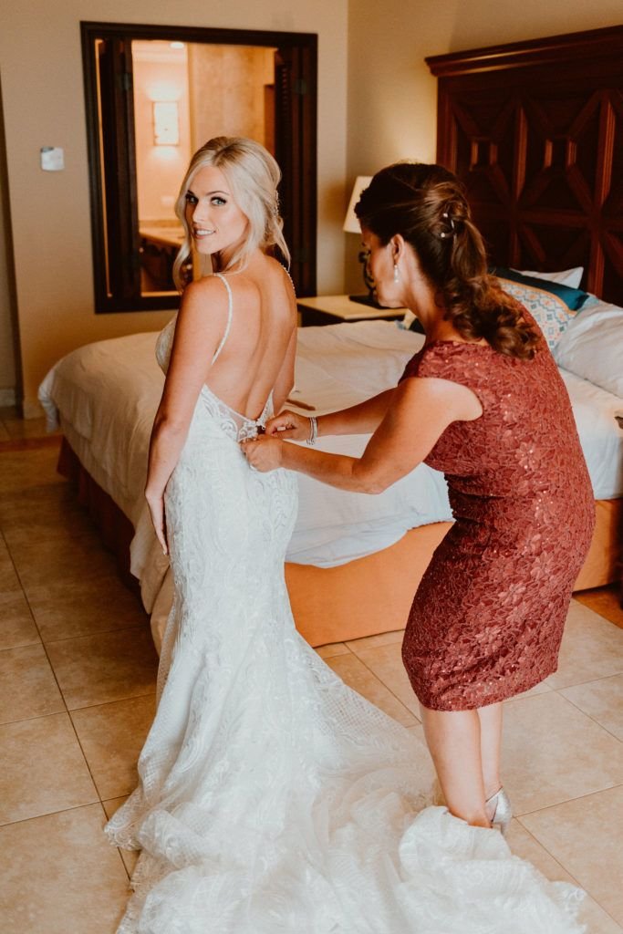 Bride Ariel getting her dress on with her mother assisting. The Bride and her Bridesmaids decided to get ready at Ariel's bridal suite at Pueblo Bonito Sunset Beach, in Los Cabos,  Mexico. The Destination Wedding took place at Acre Baja.