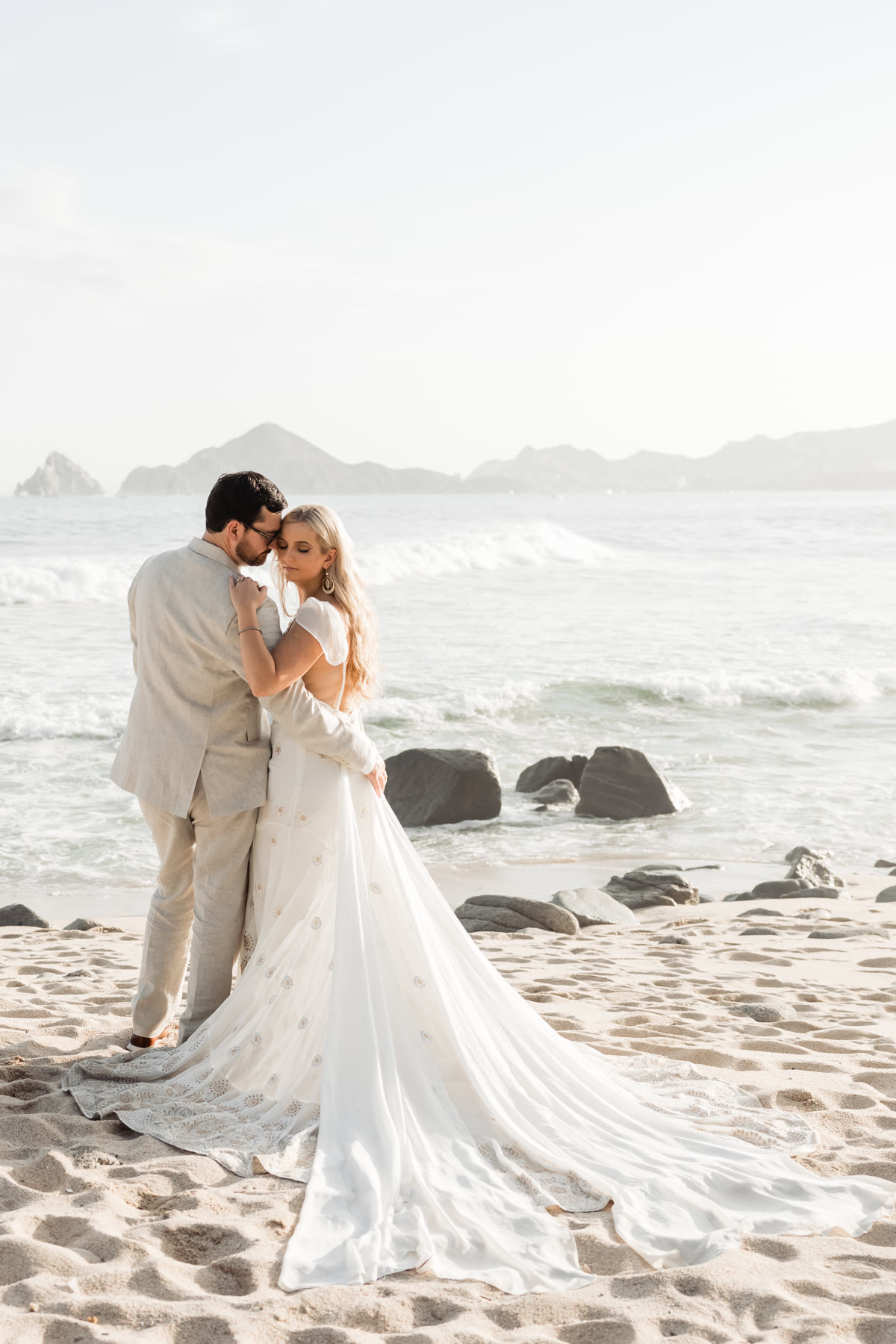 Bride and groom embracing on a Cabo San Lucas beach at sunset