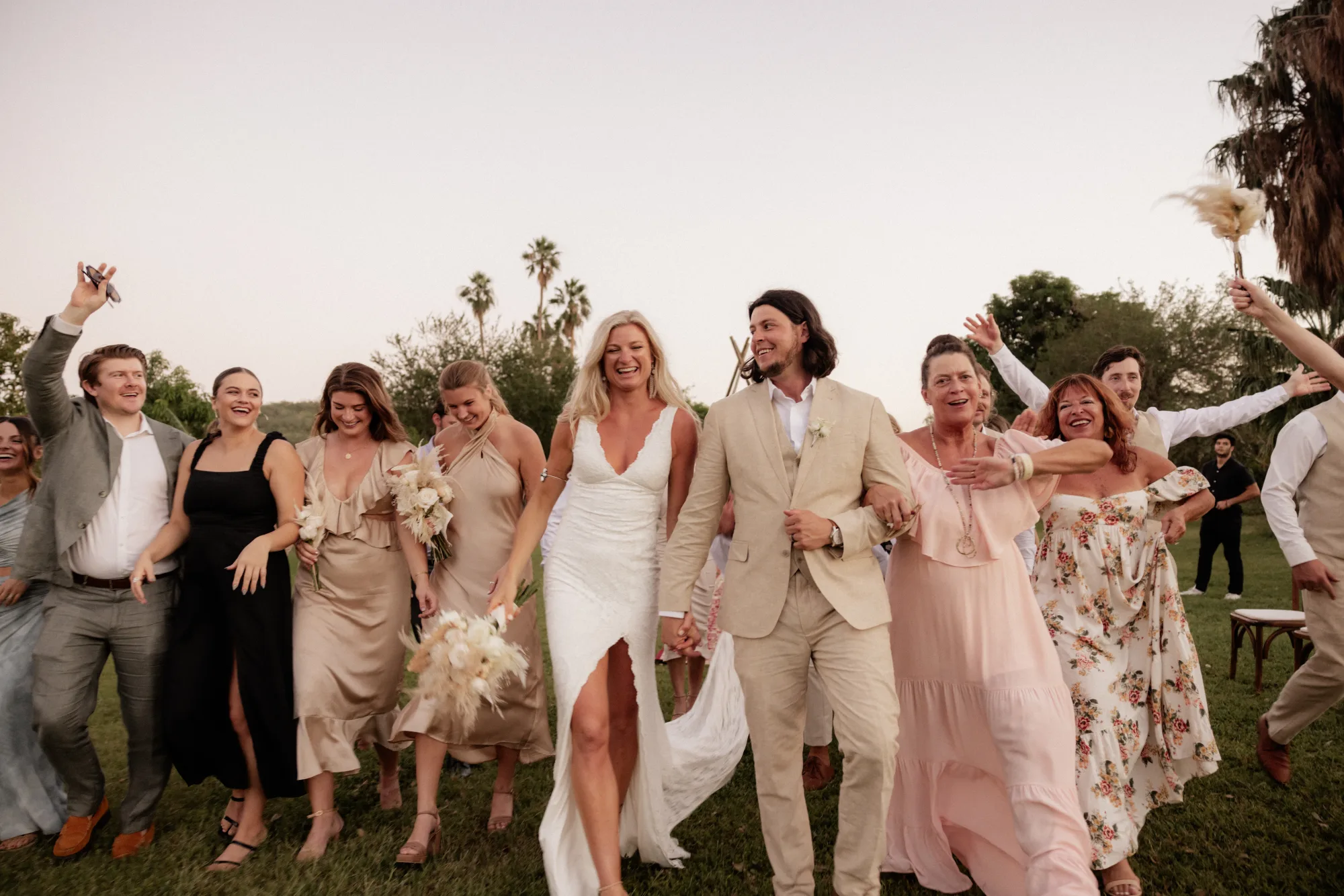 Wedding party and family walking across a lawn after a ceremony in Cabo