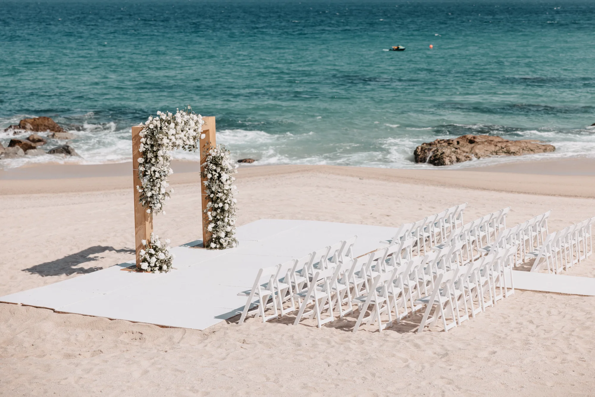 Beach wedding ceremony setup with floral arch in Cabo