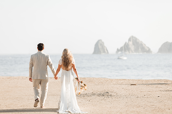 Sunset Monalisa wedding setup in Cabo San Lucas — champagne toast with Land's End backdrop